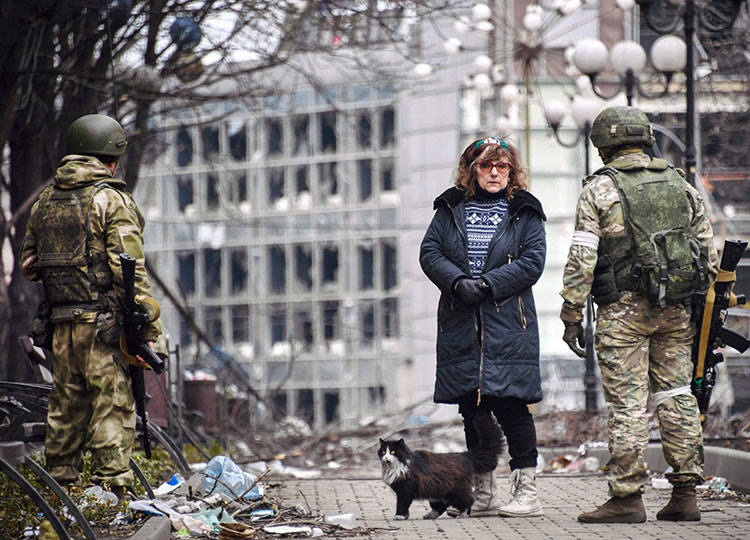 A woman talks with Russian soldiers in Mariupol, Ukraine, on April 12 as Russian troops intensify a campaign to take the strategic port city.