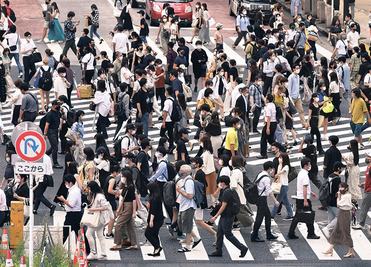 Pedestrians wearing masks walk across a crossing near Shibuya Station in Tokyo on July 30.