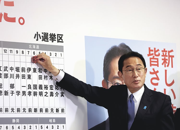 Fumio Kishida, the prime minister and leader of the ruling Liberal Democratic Party, gestures as he puts rosettes on a board with names of successful general election candidates at the party’s headquarters in Tokyo on Oct. 31.