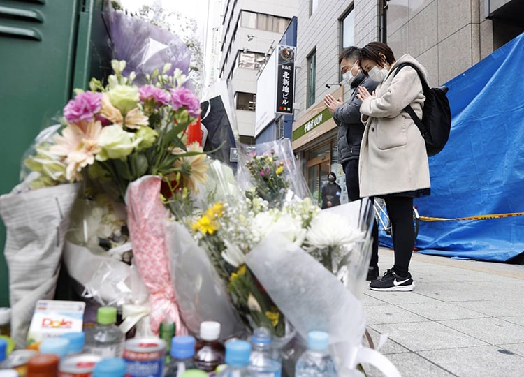 People join hands on Dec. 29 in front of a building in Kitashinchi, Osaka, where a fatal arson incident took place.