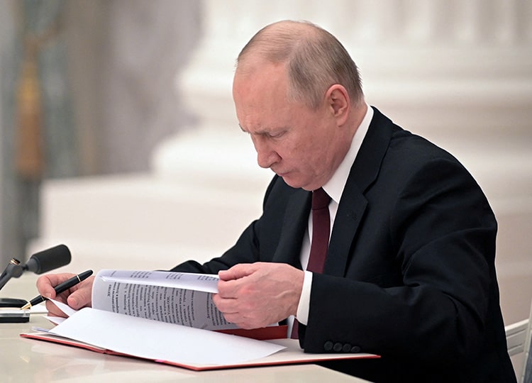 Russian President Vladimir Putin signs documents, including a decree recognizing regions in eastern Ukraine as independent, in Moscow.