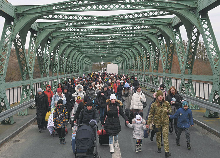 Ukrainian refugees cross a bridge at the buffer zone along the Polish border at Zosin-Ustyluh, western Ukraine, on March 6.