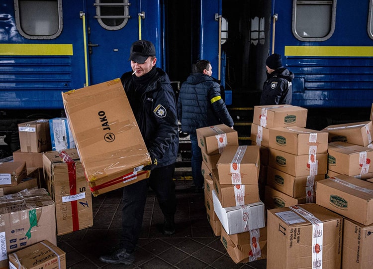 Ukrainian police officers help volunteers unload a train bringing international aid to Kyiv on March 3.